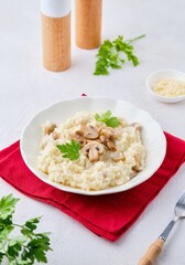 Risotto with mushrooms garnished with parsley in a light plate on a white concrete background. Risotto recipes.