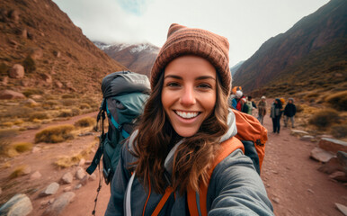 Naklejka premium Enthusiastic Young Native Woman, Backpack-Clad, Captures a Selfie While Trekking in Morocco, Near the Majestic Jebel Toubkal, the Summit Peak of the Atlas Mountains