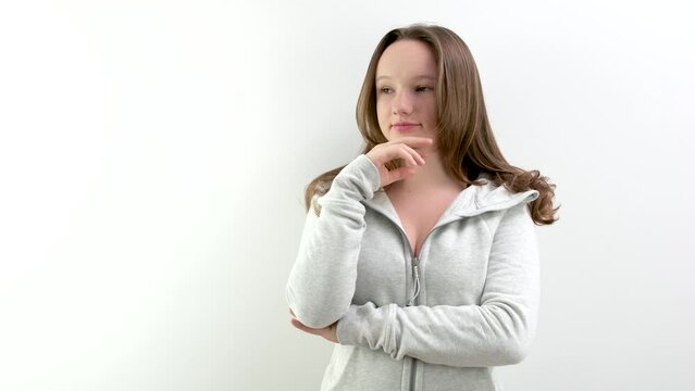 A young woman standing in front of a white wall and making a surprise gesture. High quality 4k footage
