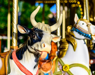 Colorful cow on traditional old french caroussel in city park in sunny day