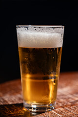 Pint glass of cold fresh british ale and lager beer served in old vintage English pub