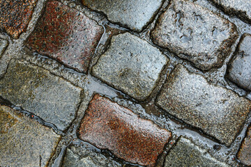 Close-up of a stone pavement, wet from the rain. Pavement background texture with geometric pattern