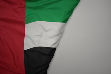 big waving national colorful flag of united arab emirates on the gray background.