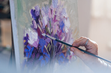 Senior woman's hands using a brush painting an oil painting with out of focus background