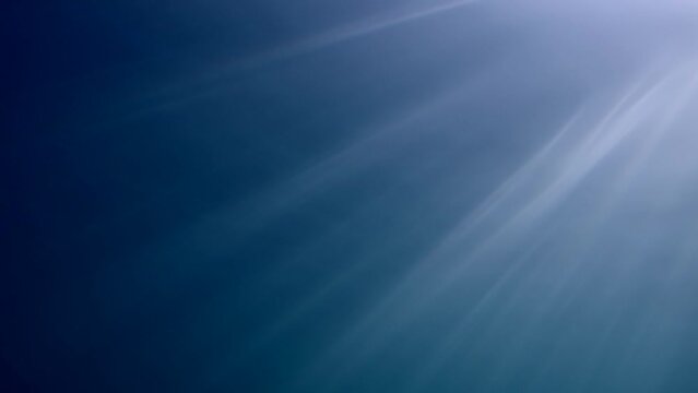 Diagonal dance sun rays luminous in Ocean. Sunshine penetrate below waters through sea surface shiny into blue water. Oblique sun beams underwater. Slanting sunburst in depth, Slow motion