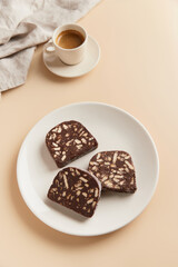 Traditional portuguese dessert Salame de Chocolate on beige background in minimal style. Homemade cocoa cake.