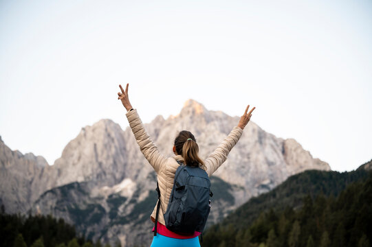 Young woman with victory arms standing looking at beautiful view of mountains