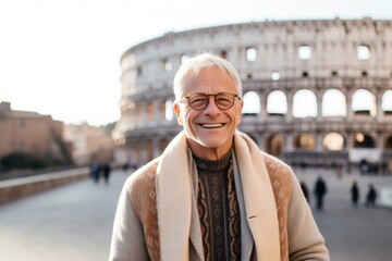 Group portrait photography of a grinning man in his 50s that is wearing a chic cardigan against the Colosseum in Rome Italy