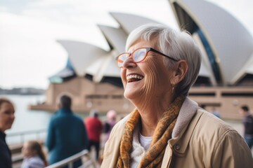 Fototapeta premium Lifestyle portrait photography of a grinning woman in her 60s that is with the family at the Sydney Opera House in Sydney Australia