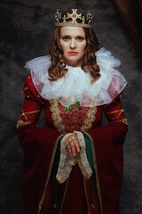 medieval queen in red dress with white collar and crown