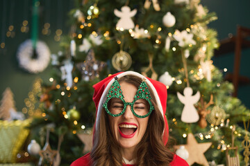 cheerful trendy woman with Santa hat in modern living room