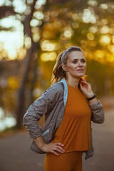 stylish woman in fitness clothes in park looking into distance