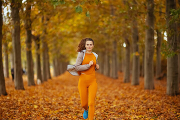 stylish female in fitness clothes in park jogging