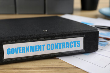 Black folder with Government Contracts label on desk in office, closeup - obrazy, fototapety, plakaty