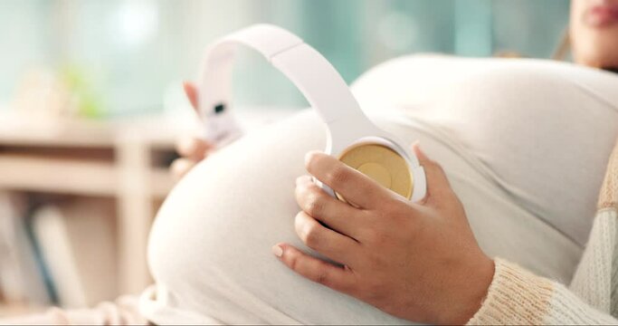 Pregnant, woman and headphones on stomach for peace, relax and music for baby in living room of home. Radio love, pregnancy and new mother streaming podcast and sound for kid therapy and calm child