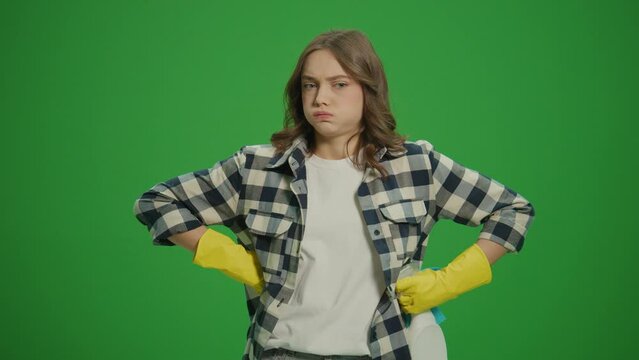 Green Screen. A Serious Young Woman in Yellow Protective Rubber Gloves,Holding a Cleaning Spray Bottle and Rag, Inspects the Amount of Cleaning.Cleaning for Mental Clarity and Focus.