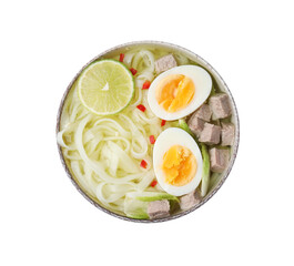 Bowl of delicious rice noodle soup with meat and egg isolated on white, top view