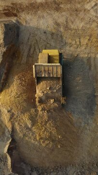 Haul Trucks conceal ground on open coal quarry. Dump Trucks. A heavy dump truck unloads sand. Sand pours from the truck. Aerial vertical, vertical video background.