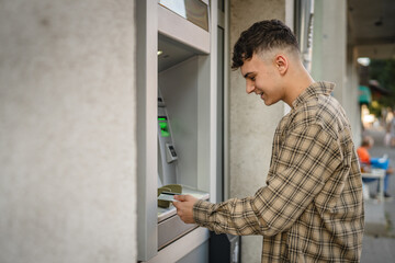 man teenage student using credit card and withdraw cash at the ATM