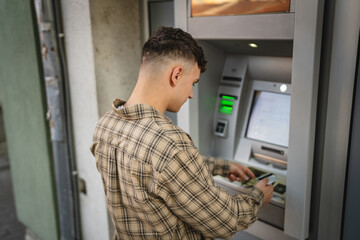man teenage student using credit card and withdraw cash at the ATM