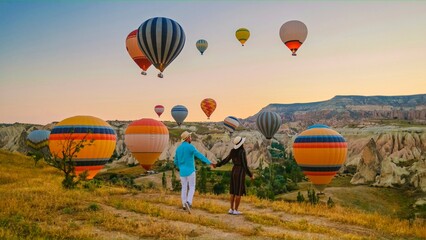 Kapadokya Cappadocia Turkey, a happy young couple during sunrise watching the hot air balloons of...