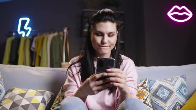 Bored young woman using phone. Woman with bored tedium tired look monotonously flips through unimpressive videos photos online news boring content. Woman wearily puts phone aside gets up from couch