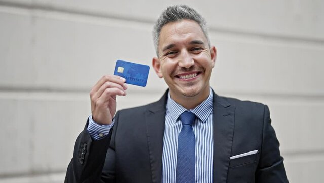 Young hispanic man business worker smiling confident holding credit card at street