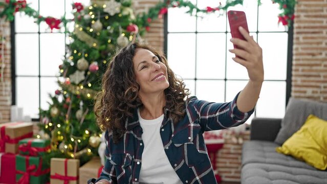 Middle age hispanic woman taking a selfie picture celebrating christmas at home