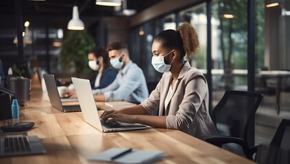 Businesswoman in protective mask working on laptop in office during pandemic