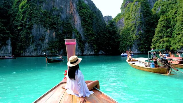 Thai women in front of a Longtail boat at Pileh Lagoon with the green emerald ocean at Koh Phi Phi Thailand during a boat trip to Maya Bay Koh Phi Phi Island
