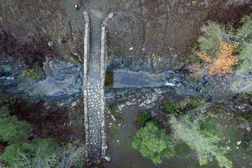 Aerial drone photograph of a medieval stoned bridge with water flowing in the river.