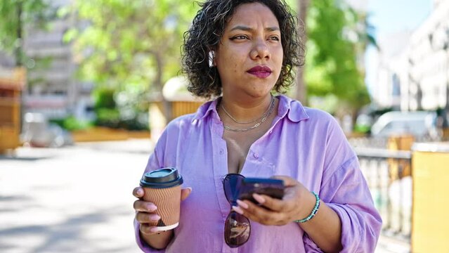 Young beautiful latin woman having free hands call holding coffee at park