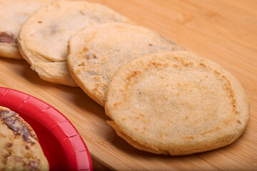Savor the rich flavors of El Salvador with pupusas, a traditional Central American dish, served with curtido and savory sauce on a rustic wooden board