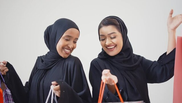 Two young women spending time together making activities. Two friends wearing the traditional emirates abaya dress making shopping in Dubai