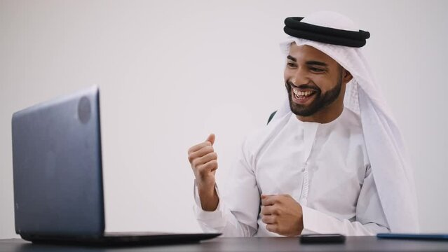 Handsome man with dish dasha working in his business office of Dubai. Portraits of a successful businessman in traditional emirates white dress. Concept about middle eastern cultures