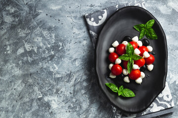Caprese with cherry tomatoes, mini mozzarella, fresh basil leaves, Traditional italian food, antipasto. banner, menu, recipe place for text, top view