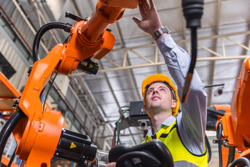 Smart modern engineer male using modern robot technology. Robotic welding arm setup in automation production process in factory