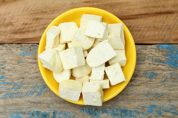 Paneer sliced in a plate on old wooden background top view 