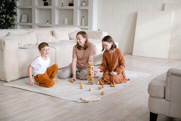 Happy Family sitting On Carpet Playing With The Wooden Blocks At Home. Young woman with son and...