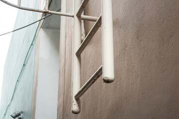 An emergency escape fixed ladder which is installed on the building wall. Close-up and selective focus at the metal rail part.