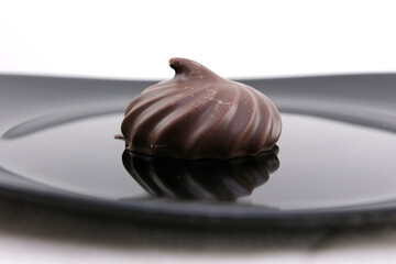 Melted chocolate is poured on a chocolate sweet and delicious chocolate covered marshmallow on a wooden table. 4K.