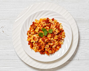 Lasagnette bolognese on white plate, top view