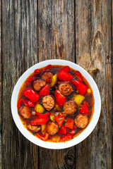 Delicious lecho - vegetables with sausages on wooden table
