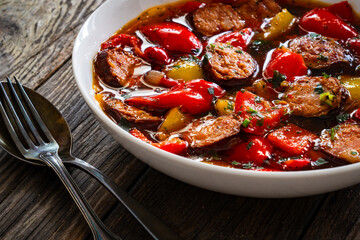 Delicious lecho - vegetables with sausages on wooden table
