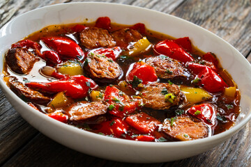 Delicious lecho - vegetables with sausages on wooden table
