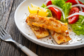 Seared cod loin and fresh vegetables on wooden table
