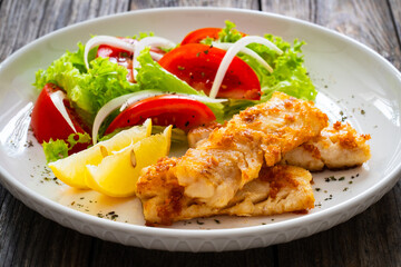 Seared cod loin and fresh vegetables on wooden table

