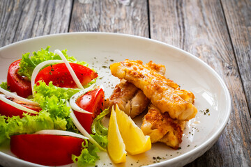 Seared cod loin and fresh vegetables on wooden table
