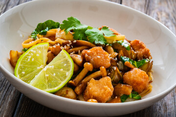 Asian food - chicken nuggets, noodles and fried shimeji mushrooms on wooden table
