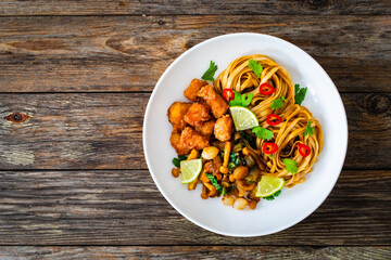 Asian food - chicken nuggets, noodles and fried shimeji mushrooms on wooden table
